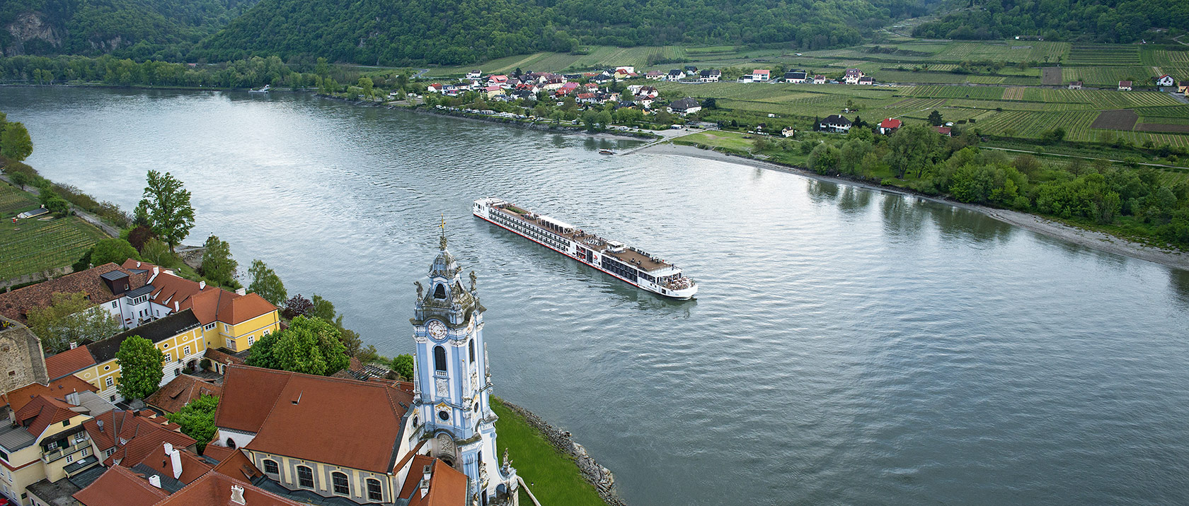 Aerial view of a Viking river ship sailing past Dürnstein, Austria along the Danube river